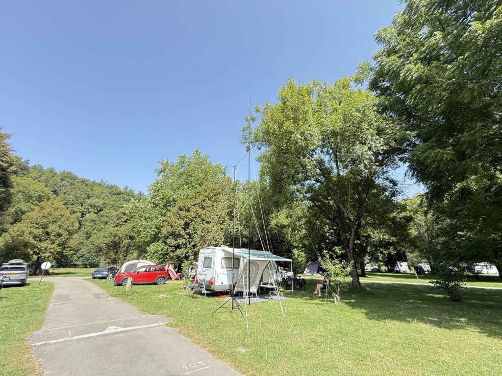 Campsite with the mobile home and the antenna between the trees